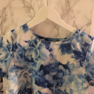  - Färgglad, ljusblå tröja. Modellen är något längre än croptop, tajt men med vidd i modellen. Liten fläck på baksidan av ena armen, annars knappt använd. 