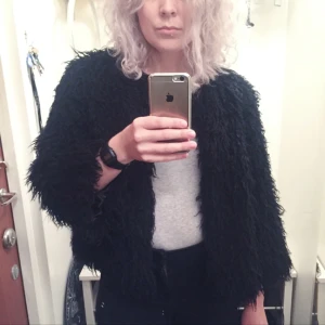  - Fluffig svart jacka från Monki. Fejkpäls i fårskinnsimitation, med glansigt innertyg. Snyggt dold knäppning och utan krage. Kan skickas mot frakt.