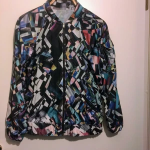  -  Assnygg jacka med massa grafiska mönster på, säljer då den inte passar längre. Står ingen storlek men uppskattar att det är en S. Har fickor med dragkedja fram och en ficka på armen. I ”vindjacka” material typ.