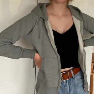 Grå hoodie - Grå hoodie med små röda detaljer. Tyvärr fungerar inte dragkedjan, därav det låga priser, men den är supefin att ha öppen över t.ex. ett linne. Storlek XS/S. Pris 50kr + frakt🌶