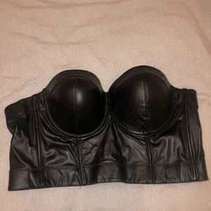 Topp i skinn imitation  - En topp i skinnimktstion som har flera spännen baktill så den passar flera storlekar 