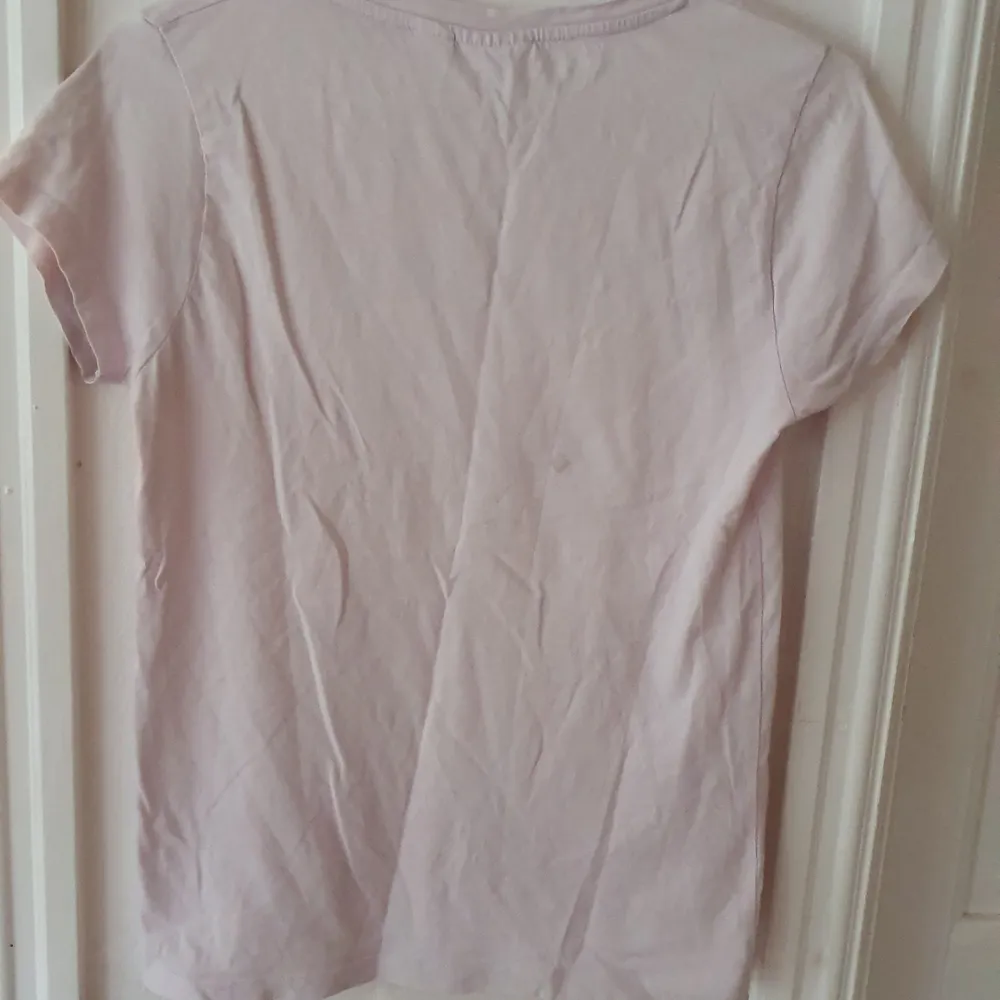 Pastellrosa t-shirt från Pusheen. Trycket är en katt med stjärtfena och texten 