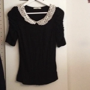  - Svart topp med virkad krage