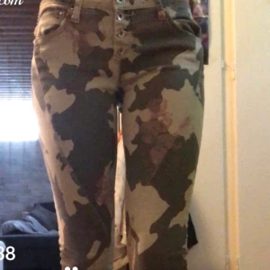 Militär byxor  - Ett par långa lågmidjade byxor med militärtryck och även lite röda märken. Använda ganska många gånger både av mig och min mamma men är i bra skick. Kan mötas upp i Ängelholm och frakta köparen står för frakt. BUDA!!!