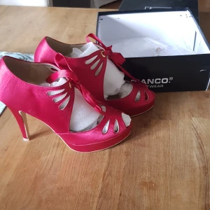 Högklackad festsko - Högklackade sandalett i studenter i djup hallonröd färg använda 1 gång. Klackhöjd 10 cm med liten platå fram. Öppen tå.