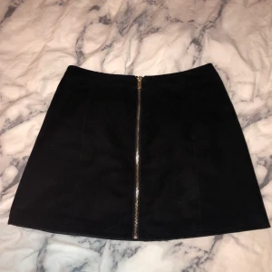 Svart kjol strl 38 - Svart kjol med dragkedja fram i storlek 38, men passar strl 34/36 också. Lite för liten för mig som oftast har M/L i byxor. Från H&M i fejkmocka med annat material inuti. Knappt använd. Kan mötas i Stockholm, annars frakt 40 kr :)