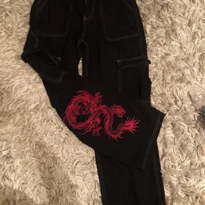 Svarta jeans med vita sömmar och tryck - Köpte dessa as balla byxor på Urban outfiters för ca 5 månader sedan. De kommer tyvärr inte till så mycket använd så säljer dem istället. Vita sömmar och as ballt drak tryck på baksidan.  Modell: skate alltså vida. Högmidja. Nypris: 1200kr jag är 168 cm