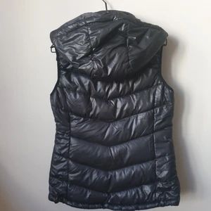 Väst - Svart väst med avtagbar luva. Luvan fästs med dragkedja som annars ligger dold när luva inte sitter på (se bild) passar storlek XS / S / 34 / 36. Kan hämtas i södra Stockholm.