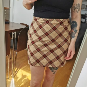 Rutig kjol - Midjemått 76 cm, längd 45 cm. Dragkedja i sidan. Jag har lagt upp den lite i nederkant. Köpare står för porto. 