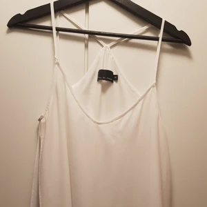  - Vitt linne med korsande tunna band, lite av en boxercut baktill, flowig form med en tightare innandel och lite kortare ovandel. Lätt uringgad.