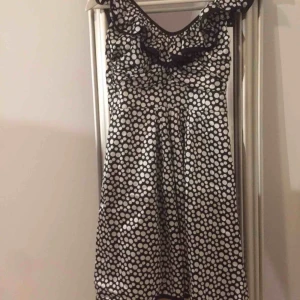  - Otroligt snygg klänning med en volang upptill vid bysten som sträcker sig bak i rygg, där man även knyter på sig klänningen. Glansigt, glatt tyg, svartvitprickig. Passar xs med normal/stor byst alt s med liten/normal byst Aldrig använd (för lliten)