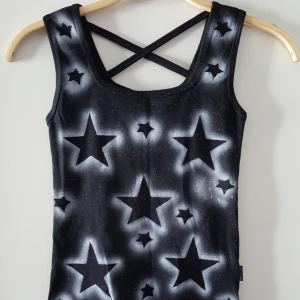  - Svart linne med vita stjärnor och band i ryggen. Står ej storlek men ca som XXS/XS skulle jag säga, lite stretchig. Fraktkostnad blir 45kr.