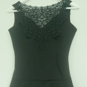  - Svart peplum-blus med spets framtill i scuba-diver aktigt tyg. Sparsamt använd. storlek 38/M.