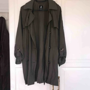  - En militärgrön trenchcoat i storlek 38.