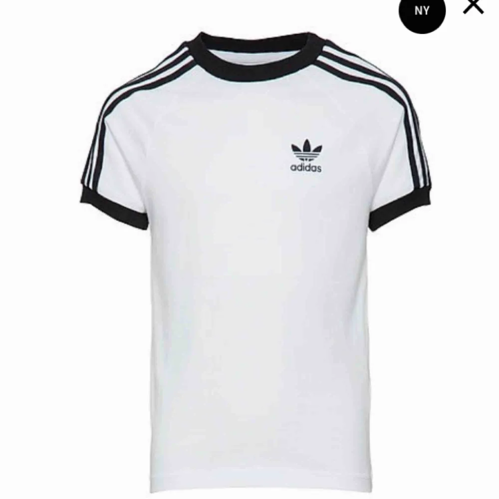 Vit och svart t-shirt med sträck på armarna från Adidas i storlek L. Använd men som ny. Köparen står för eventuell fraktkostnad . T-shirts.