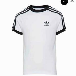 Vit och svart t-shirt med sträck på armarna från Adidas i storlek L. Använd men som ny. Köparen står för eventuell fraktkostnad 