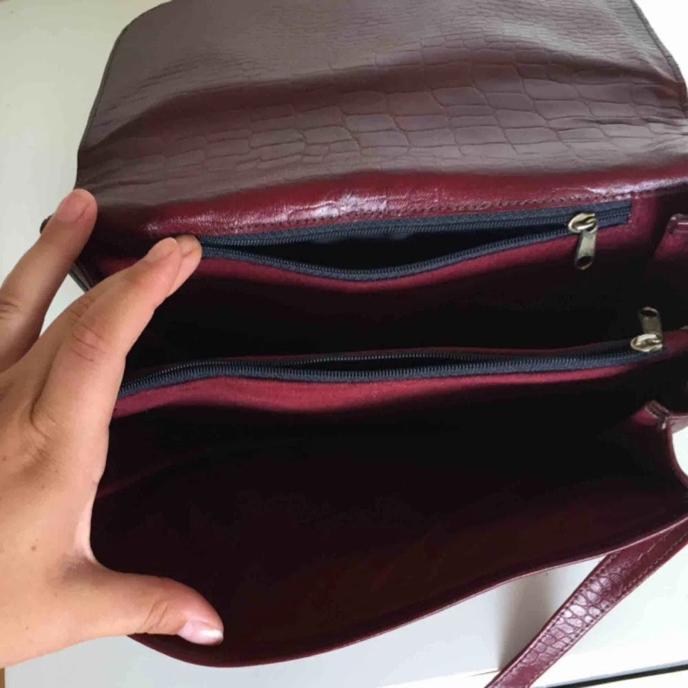 Vinröd handväska! Köpt second hand och har knappt använt den sedan dess, jättefint skick. Praktisk med två stora och två små fack (bild 3). Väskor.