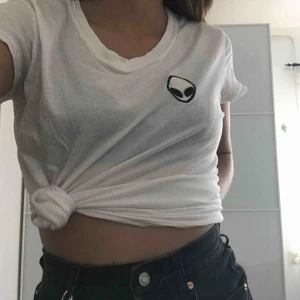  - Vit, tunn t-shirt från Brandy Melville med ailien märke på bröstet. 