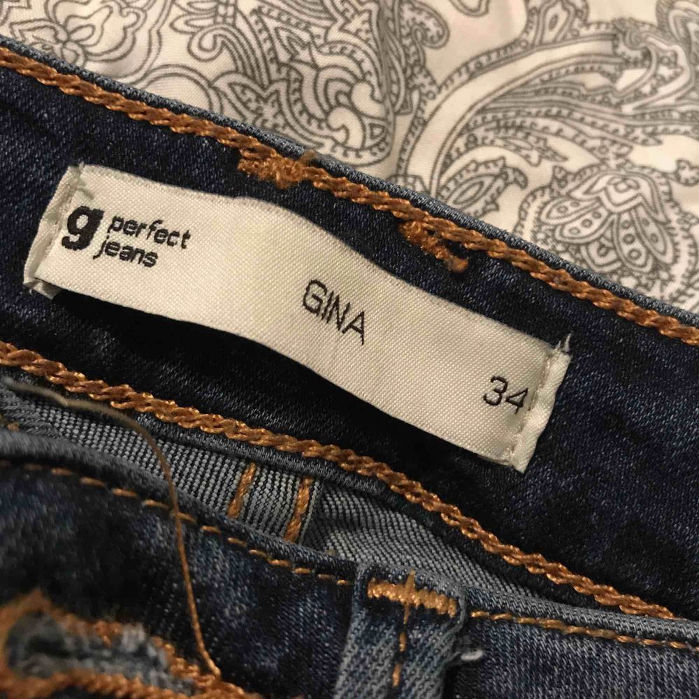 Ett par högmidjade blåa jeans med hål på knäna från Gina Tricot.Använd några gånger men är inget fel på dom.Köparen står för frakten!😊. Jeans & Byxor.