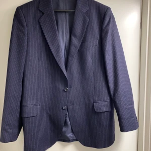 Kritstrecksrandig kavaj - Säljer denna supersnygga kavajen med kritstreck i marinblått. Kavajen är köpt här på Plick men den kommer dessvärre inte till användning hos mig. Står ingen storlek men skulle säga att den är i 40-42. Sitter oversized på mig som vanligtvis har 36. Funkar lika bra som en jacka. Skickar gärna om köparen står för frakt 🌸