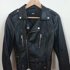 Kort svart skinnjacka med dragkedjor, XS - En kort svart skinnjacka från BikBok. Är figursydd och ger snygg form. Sned dragkedja fram för snygg passform. Mycket fint skick! 