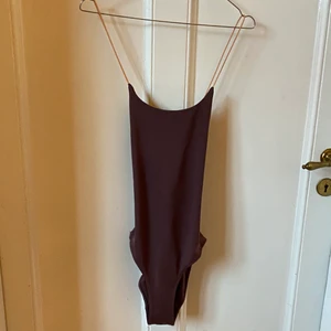 Weekday lila baddräkt med orangea band - Baddräkt med öppen rygg och korsade elastiska band. Plommonfärgad med aprikosfärgade band. Går att använda som body. Knappt använd pga för liten. Superfin😩🙏💞