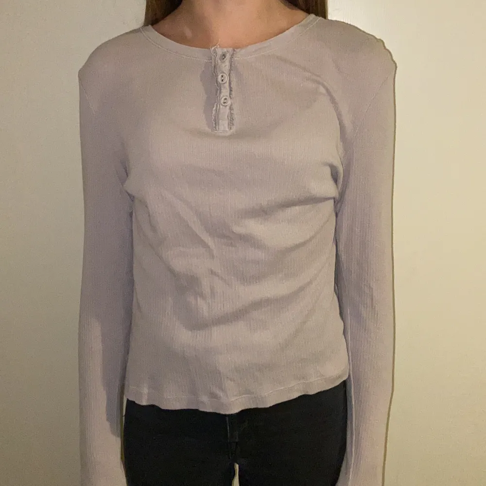 Denna långärmade tröjan är lilagrå i färgen. Den är i vad vi tror storlek M. Modellen på bilden har S i vanliga fall men är liite för stor på henne. Det är stretchigt material. Köparen står för frakten.. Tröjor & Koftor.