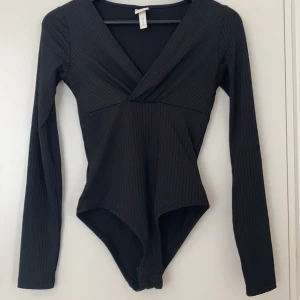 V ringad body H&M - En svart v ringad body från H&M. Använt ca 2 gånger, bra skick. Fraktkostnad tillkommer.