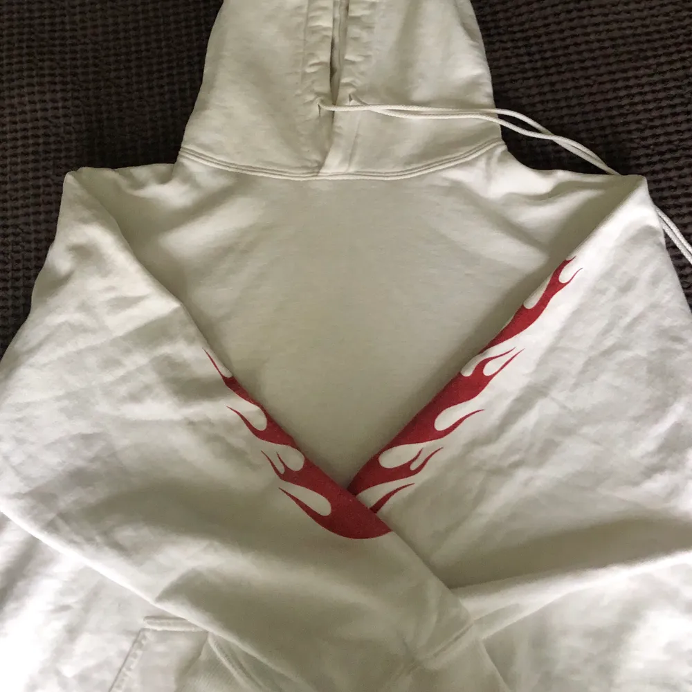 Vit Brandy Melville hoodie med röda ”flames” på ärmarna. Använd ett fåtal gånger. One size men sitter som en S/M! Frakt 75kr. Toppar.