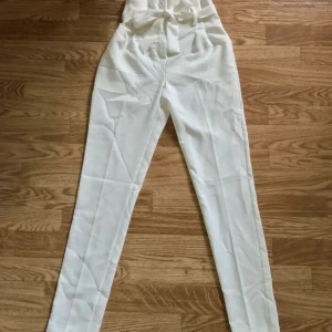Vita kostymbyxor  - Vita kostymbyxor med band runt midjan. Aldrig använda. 