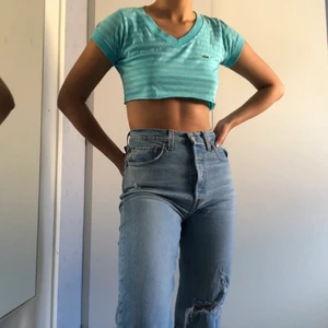 Blå Lacoste croptop - En tshirt från Lacoste avklippt till en snygg croptop. Croptopen är lätt att stylea och passar till allt