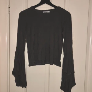  - Mörkgrå tröja mes volangärmar. I väldigt gott skick. Köpare betalar frakt.