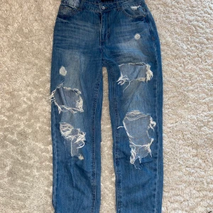 Jeans med slitningar - Tuffa jeans med mycket slitningar. Använt få gånger så väldigt bra skick. Står storlek S, men skulle säga mer som XS