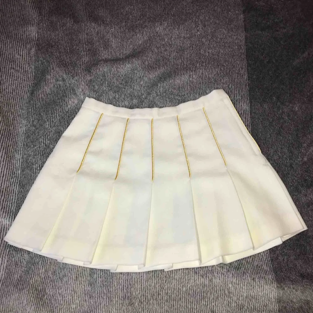 Vintage cheerleader kjol köpt på beyond retro, vit med guldiga detaljer, Använd 1 gång, passar storlek S/M, perfekt för halloween/inspark. Kjolar.