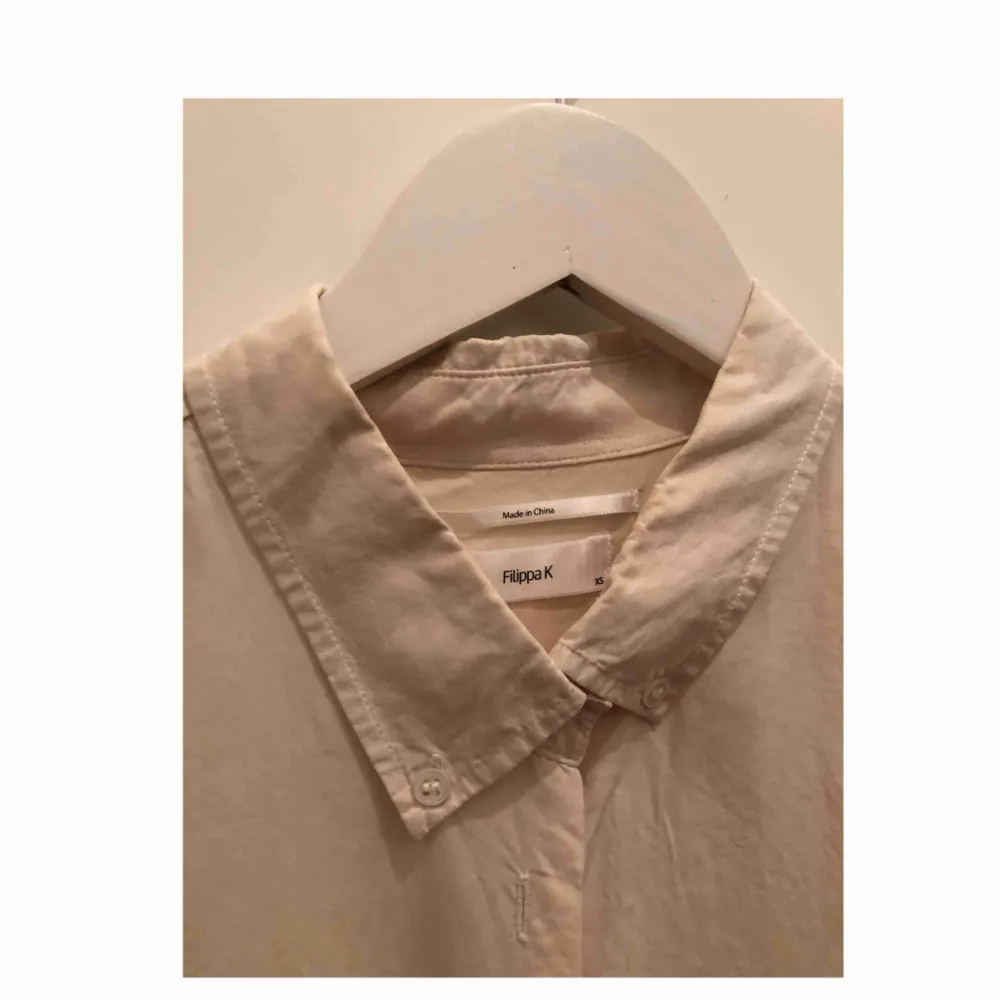 Sidenskjorta från Filippa K i benvitt/cremefärg, längre modell. Har ett litet hål på ärmen men inget som märks, annars i fint skick :). Skjortor.