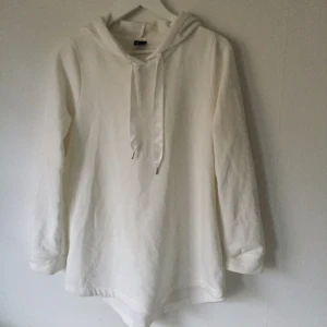  - Fin något oversize hoodie i off-white, med stor luva med breda sidenband. Längre modell med rundad nederkant. Nyskick,