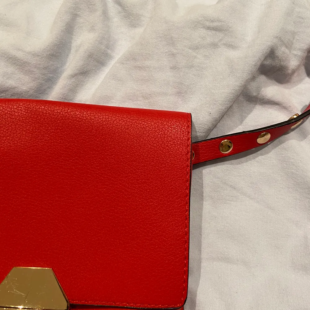 En röd väska med guldiga detaljer som funkar som både magkänsla och axelväska. Väskan är från Zara och priset är 70kr ❤️:). Accessoarer.