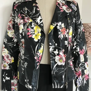 Ny snygg River Island jacka i biker modell stl 38 - Super snygg jacka som passar till det mesta. Fickor fram och med svart botten och blommigt mönster. Fuskskinn men ser ut som äkta! NYTT!