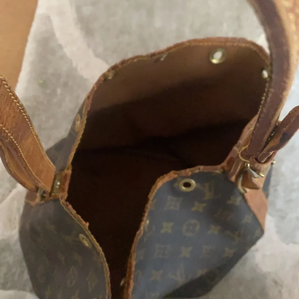 Äkta vintage Louis Vuitton väska. Det är en bucket bag men saknar snöret men snöret går enkelt att få tag på.  Den är vintage och har en missfärgning på sidan se på bild tre. Har du intresse kan du få fler bilder på väskan.. Väskor.