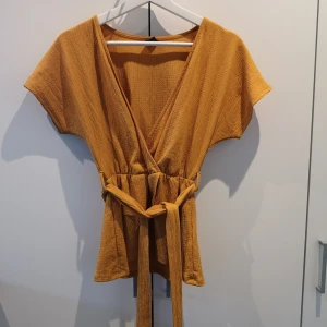 Orange omlottstopp från Gina Tricot  - En fin sommartopp från Gina Tricot. Omlottsmodell. Storlek XS! 