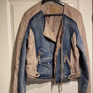 Jeansjacka i strl 42 - Jättefin jeans/skinnjacka från Amisu i strl 42. Mycket fina gulddetaljer på både framsida och armar. Använd 1 gång och i mycket fint skick.