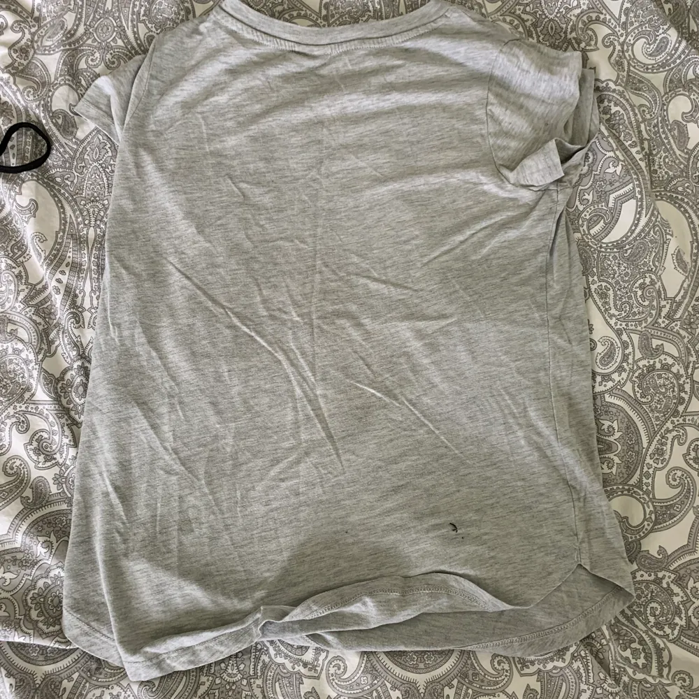 En grå T-shirt med svart tryck i storleken xs från gina tricot. Är använd en del och finns knotter på den men annars inga märken/fläckar. 25kr +frakten 👍🏽. T-shirts.