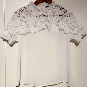 söt Blus - Elegant söt blus med massa spets och volang. I nyskick och storlek  är i S passar nog till en stor XS också. Knapp i ryggen. Köparen står för frakten. 🌸