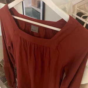Höstig Blus  - Härlig höstig blus i bra kvalitet med fina detaljer på ärmar samt nedre kant, blusen är mörktkoppar färgad. Luftigt tyg men ej genomskinlig 