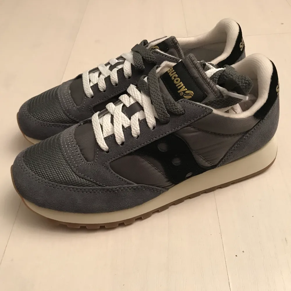 Helt oanvända supersköna Saucony sneakers i originalförpackning. Storlek 39, 24.5cm. Gråa med svarta detaljer. Kan skickas. Köparen står för frakt. (+63kr) med postnord spårbart. Skor.