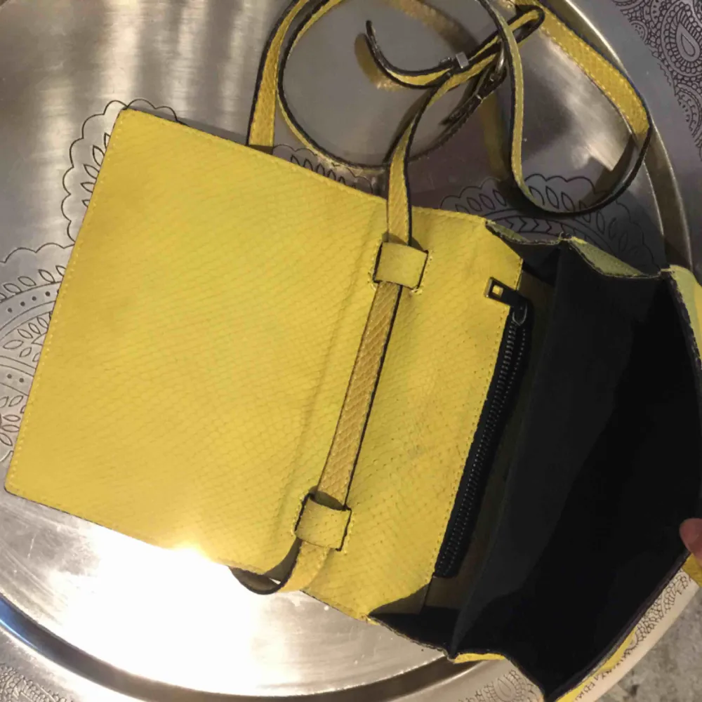 En jättefin gul väska i fake ormskinn, den är i begagnat skick men fortfarande jättefin!!. Accessoarer.