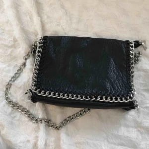  - Svart Pricilla väska från Tiamo i storlek M. Har några slitningar på metallen vid knäppningen och dragkedjan och en av läderremmarna har lossnat på väskans framsida, men syns knappt och går att sy fast igen! Nypris: 499. 🌹 Frakt tillkommer!