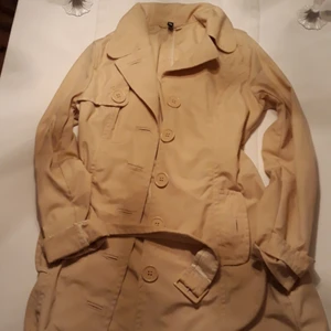  - Tunn beige lång trench coat! Som ny. Stl 38 hämtas i Mehedeby,kan tas till Tierp!