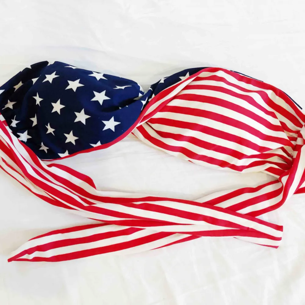 Bikiniöverdel med amerikanska flaggan på. Knyts i bak. Har formpressade kupor. . Övrigt.