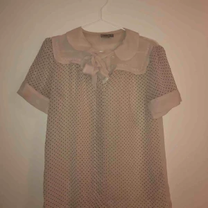  - Prickig blus från ASOS i tunt tyg. Storlek 34/XS och har snören fram att knyta till en rosett. Tar bud. 